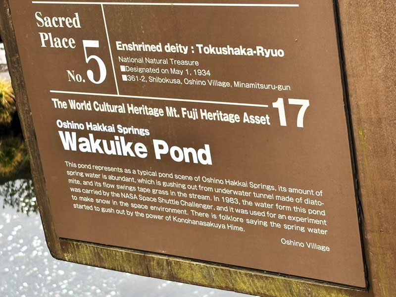 Information sign for Wakuike Pond at Oshino Hakkai Springs, detailing its significance and historical context.